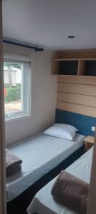 a small room with two beds and a window at Camping les salins de la gardiole, mobile home 6 personnes in Vic-la-Gardiole