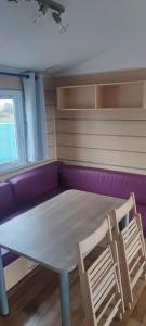 mesa y sillas en una habitación con sofá púrpura en Camping les salins de la gardiole, mobile home 6 personnes en Vic-la-Gardiole