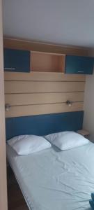 a bed with a headboard and a white pillow at Camping les salins de la gardiole, mobile home 6 personnes in Vic-la-Gardiole