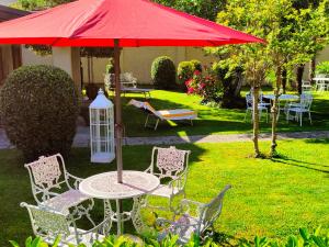 een tafel en stoelen onder een rode paraplu in een tuin bij Villa DaVinci in Verbania