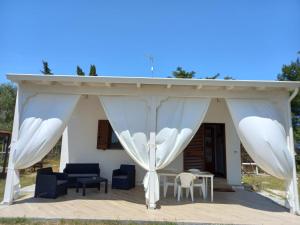 einen Pavillon mit weißen Vorhängen sowie einem Tisch und Stühlen in der Unterkunft Villa Raffaella in Lecce
