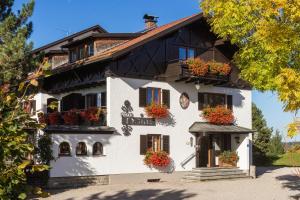 un bâtiment blanc avec des boîtes de fleurs sur ses fenêtres dans l'établissement Pension Heim, à Seeg