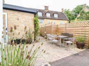 a patio with a table and chairs and a fence at Ruskin House in Moreton in Marsh