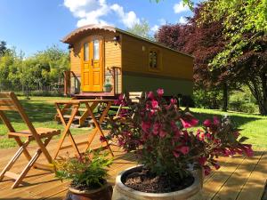 een tiny house met een picknicktafel en bloemen bij Roulotte La Chouette des Granges in Les Salles-Lavauguyon
