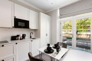 a kitchen with white cabinets and a table with chairs at PenthouseStays Chelsea - Luxury King / Queen Bed Studios - near King's Road in London