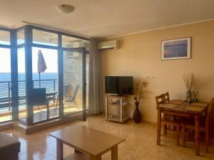 a living room with a table and a television and a balcony at Dolce Vita Apartment in Sveti Vlas