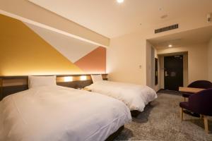 a hotel room with two beds and a chair at Hotel Kanazawa in Kanazawa