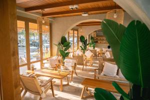 un restaurante con sillas, mesas y ventanas en The Tide Resort en Bangsaen