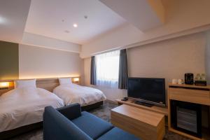 a hotel room with two beds and a flat screen tv at Hotel Kanazawa in Kanazawa