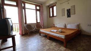 a bedroom with a bed and a tv and windows at Sarthak Home Stay, Beautiful Valley view of Mountain in Jagatsukh
