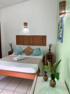 a bedroom with two beds and a table with a plant at Pousada Lanai in Itacaré