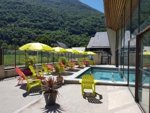 una piscina con sillas y sombrillas en un edificio en Le Village Vacances de Luz Saint Sauveur en Luz-Saint-Sauveur