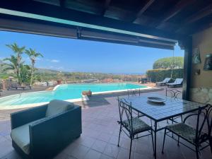 um pátio com uma mesa e cadeiras e uma piscina em Villa Carly Taormina apartment with private pool em Trappitello
