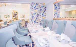 a dining room with white tables and blue chairs at AX The Victoria Hotel in Sliema
