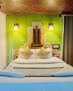a bedroom with a large bed with a green wall at Wild Elephant Resort in Kallar Vattiyar