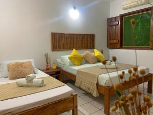 Habitación de hotel con 2 camas con almohadas amarillas en Pousada Lanai, en Itacaré