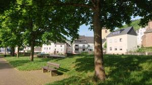ein Park mit einer Bank, Bäumen und Gebäuden in der Unterkunft Ferienwohnung Familie Boemer in Alf