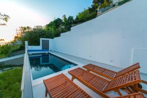 uma casa com piscina e dois bancos de madeira em Villa Marinkica em Brela