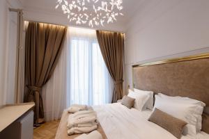 um quarto com uma grande cama branca e um lustre em The Crown Boutique Hotel & SPA em Tirana