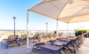 a group of chairs and tables under a tent on a roof at AX The Victoria Hotel in Sliema