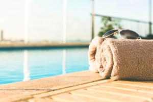 Un paio di occhiali da sole seduti su un asciugamano vicino alla piscina di AX The Victoria Hotel a Sliema