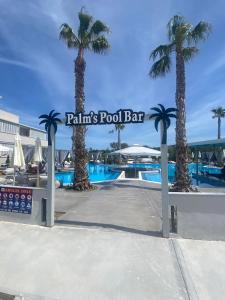 une piscine bordée de palmiers et un panneau indiquant un bar. dans l'établissement Anna Hotel, à Pefkohori