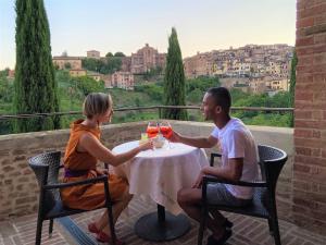Villa del Sole Siena في سيينا: رجل وامرأة يجلسان على طاولة مع كؤوس للنبيذ