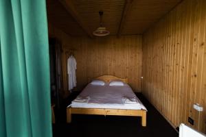 a small bedroom with a bed in a wooden wall at ТУРБАЗА NESTER-HOUSE in Svityazʼ