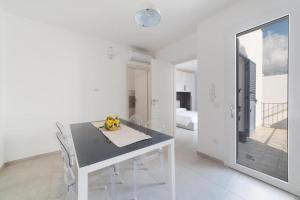 a white dining room with a table and a mirror at Quintino Apartments Pool in Torre Lapillo