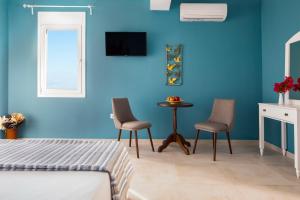 1 dormitorio con paredes azules, 2 sillas y mesa en Evi Boutique Rooms, en Galatás