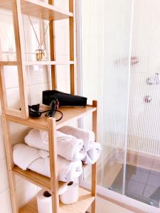 a bathroom with a shelf with towels and a shower at Villa AURA in Hévíz