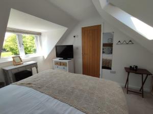 a white bedroom with a bed and a television at Little Fisher Farm - Farm-View Retreat in Chichester