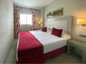 a hotel room with a large bed with red pillows at Ona Marinas de Nerja Spa Resort in Nerja