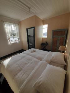 a large white bed in a bedroom with two windows at Cozy room in the Heart of Simon's Town in Cape Town