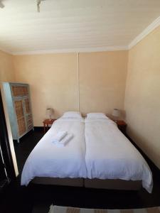 a bedroom with a large bed with two white pillows at Cozy room in the Heart of Simon's Town in Cape Town