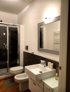 ein Badezimmer mit einem Waschbecken, einem WC und einem Spiegel in der Unterkunft Emma Home adiacente alla Piazza Ducale in Vigevano