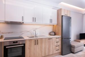 a kitchen with white cabinets and a stainless steel refrigerator at Lithies Zante Living in Zakynthos