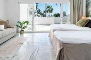 a white bedroom with a bed and a couch at Stunning 4-Bedroom Townhouse with Breathtaking Views in Marbella in Marbella