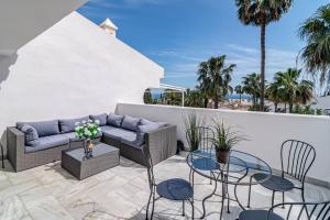 une terrasse avec un canapé, des chaises et des palmiers dans l'établissement Stunning 4-Bedroom Townhouse with Breathtaking Views in Marbella, à Marbella