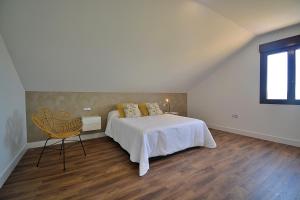 Un dormitorio blanco con una cama y una silla. en GALIHOST - Casa Esclavi, en Cambados