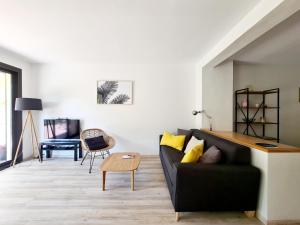 a living room with a black couch and a table at Jardin Privé ds le Centre de Cassis - Parking - Plage à 500m in Cassis