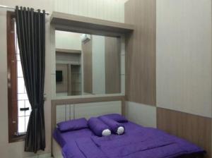 a bedroom with a bed with purple pillows and a mirror at Kedai Oma Syariah Mitra RedDoorz in Gandasoli