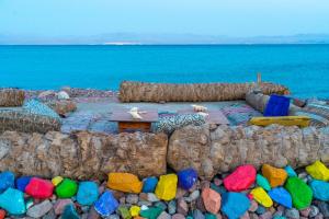 タバにあるSakraTah Camp - eco friendlyのテーブルと色とりどりの岩と海を望むビーチ