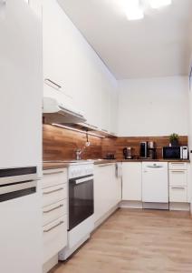 a white kitchen with white appliances and wooden walls at Niinivaara apartment saunallinen ja ilmastoitu majoitus in Joensuu