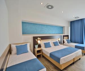 a bedroom with two beds with blue and white pillows at Hotel Luxor Florence in Florence