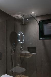 a bathroom with a shower with a mirror and a tv at Aspri Petra Apartments in Hersonissos