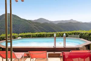 a swimming pool with chairs and mountains in the background at Villa La Casa di Giacomo in Pigna