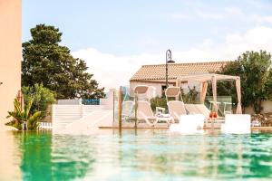 a pool of water with chairs and a gazebo at Hotel Baglio Di Scopello in Scopello