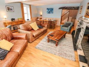 a living room with leather furniture and a fireplace at Glan y Mor in Haverfordwest