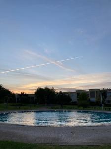 une grande piscine d'eau dans un parc au coucher du soleil dans l'établissement Résidence du golf, à Fès